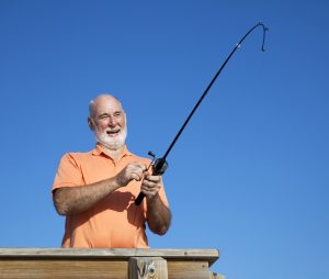 Senior man having a great time reeling in a big fish.