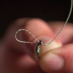 Man hand tying a fishing hook. Tie the rig. Selective focus. Tie Hook Close Up. Tie Fishing Hook Tying a fishing hook Process. Tie the KD rig and catch more carp.